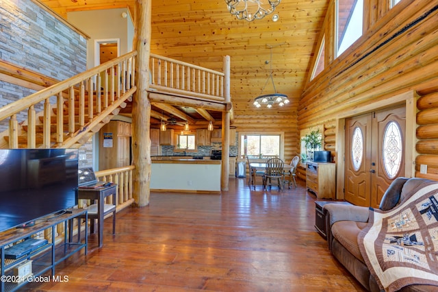 living area featuring hardwood / wood-style floors, high vaulted ceiling, log walls, stairs, and a chandelier