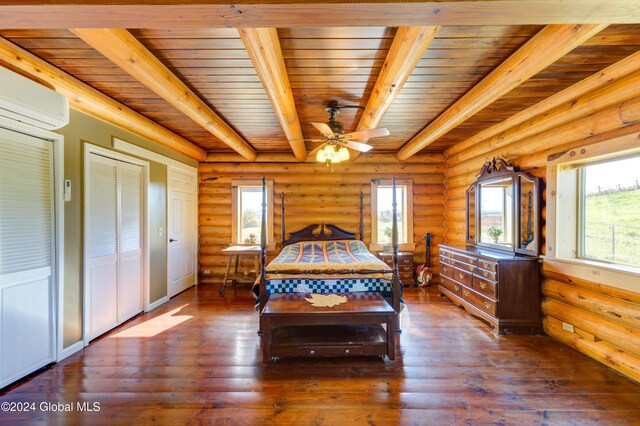 bedroom with an AC wall unit, beamed ceiling, wood finished floors, and rustic walls