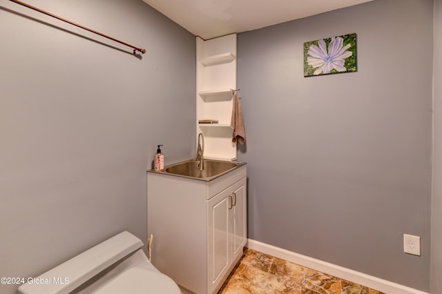 bathroom featuring toilet, baseboards, and a sink