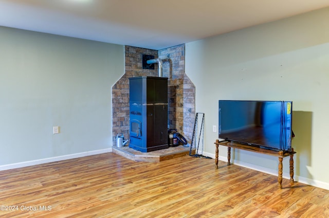 living area featuring a wood stove, baseboards, and wood finished floors