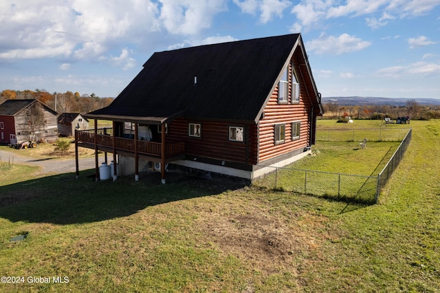 back of property featuring log siding, a lawn, a deck, and fence