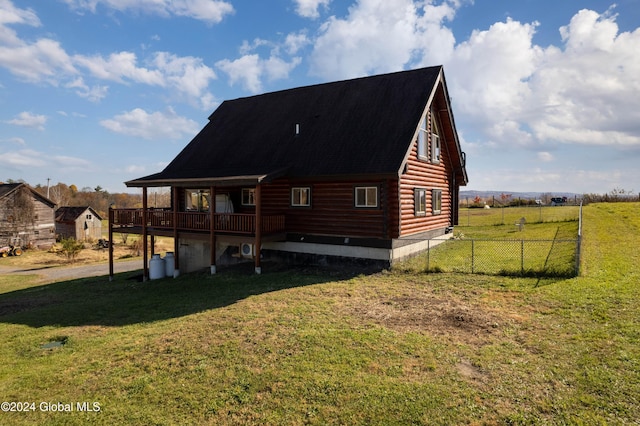 back of property with a wooden deck, a yard, and fence