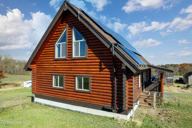 view of side of home featuring a lawn, log exterior, and fence