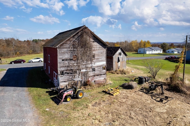 view of property exterior with an outbuilding, a barn, and a yard