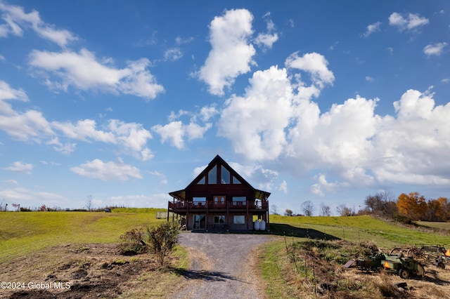 view of front of house featuring a rural view, gravel driveway, and a front lawn