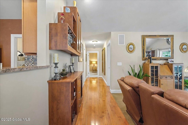 hall featuring visible vents, baseboards, and light wood finished floors