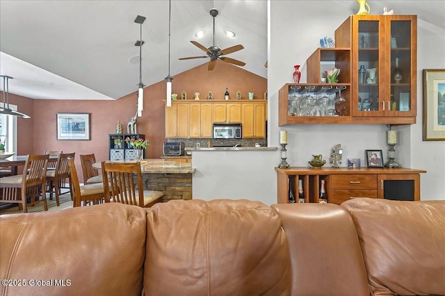 kitchen featuring stainless steel microwave, backsplash, glass insert cabinets, open floor plan, and a ceiling fan