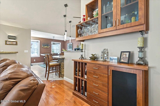 bar with light wood-style flooring, baseboards, and pendant lighting