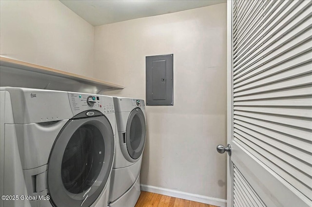 laundry room with washing machine and clothes dryer, baseboards, light wood-type flooring, electric panel, and laundry area