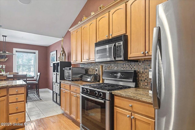 kitchen featuring stone countertops, decorative backsplash, appliances with stainless steel finishes, and a toaster