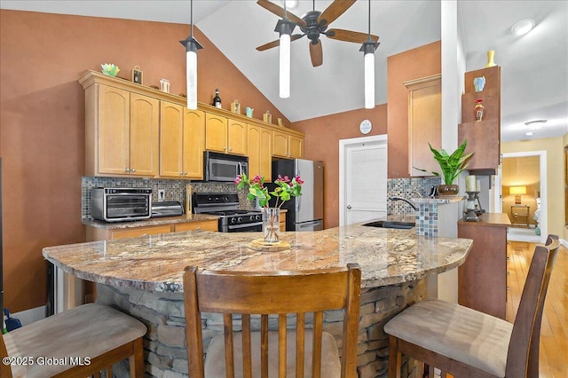 kitchen with a sink, tasteful backsplash, a peninsula, appliances with stainless steel finishes, and a breakfast bar area