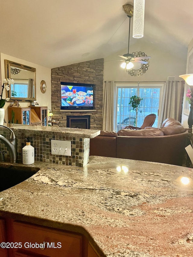 living room with a ceiling fan, lofted ceiling, and a fireplace