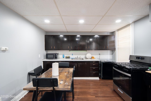 kitchen with light countertops, gas range oven, dark wood-style flooring, and a sink