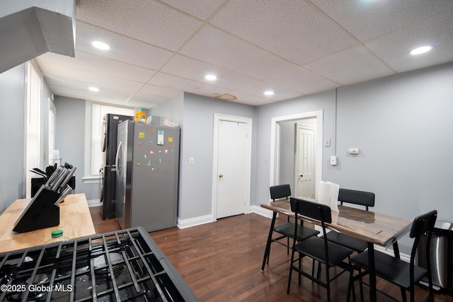 dining space with dark wood finished floors, recessed lighting, a paneled ceiling, and baseboards