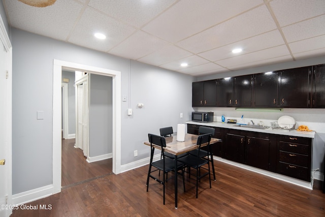 kitchen featuring dark wood-style flooring, light countertops, black microwave, and a sink