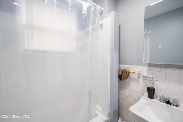 full bathroom featuring curtained shower, tile walls, and a sink