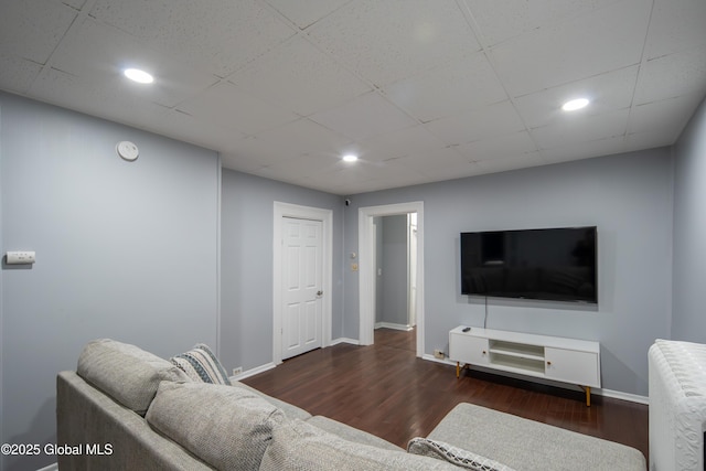 living area with a drop ceiling, baseboards, and wood finished floors