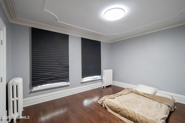 bedroom featuring ornamental molding, radiator heating unit, baseboards, and wood finished floors