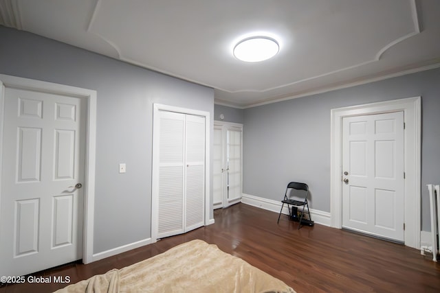 bedroom featuring a closet, baseboards, and dark wood-style flooring