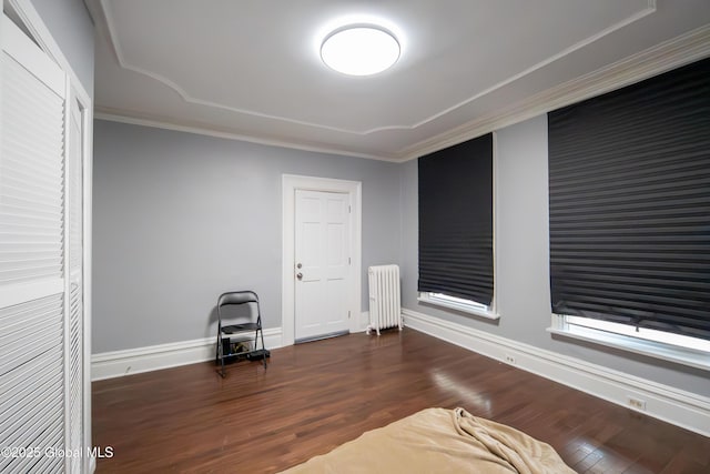 sitting room with dark wood-style floors, radiator, baseboards, and ornamental molding