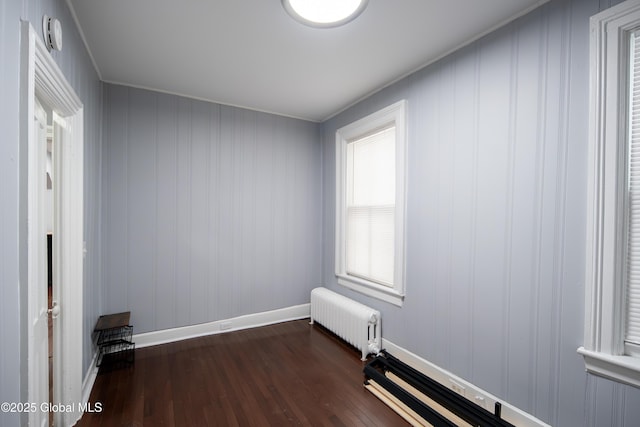 empty room featuring radiator, baseboards, and dark wood-style flooring