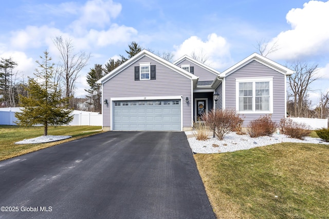 traditional home featuring aphalt driveway, an attached garage, a front yard, and fence