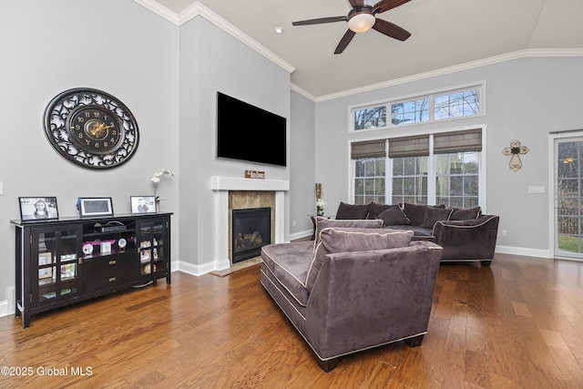 living area featuring wood finished floors, baseboards, high vaulted ceiling, a fireplace, and ornamental molding