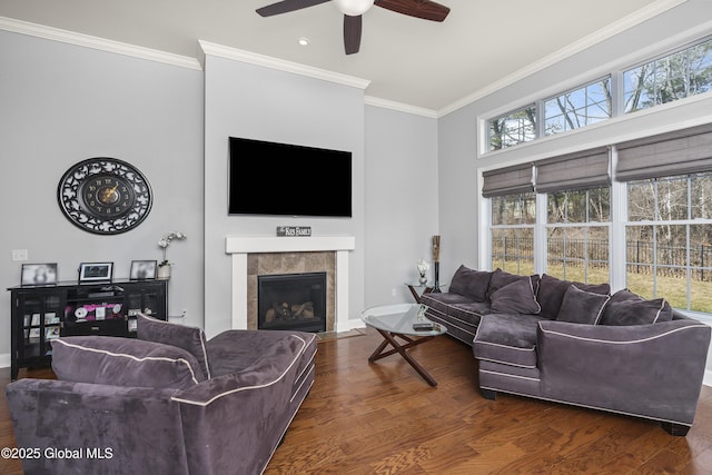 living area featuring baseboards, wood finished floors, ornamental molding, and a tile fireplace