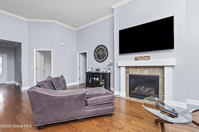 living area featuring ornamental molding, a fireplace, baseboards, and wood finished floors