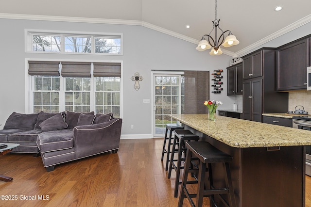 kitchen featuring dark wood finished floors, lofted ceiling, range, and ornamental molding