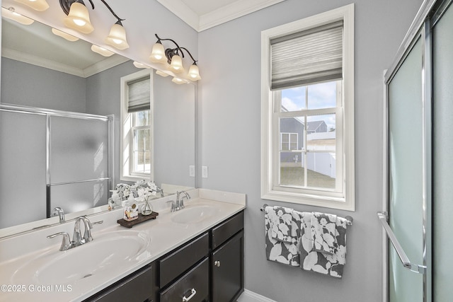 full bath with a sink, a shower with shower door, double vanity, and crown molding