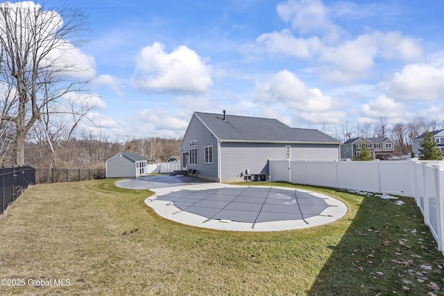 view of pool with a fenced in pool, a yard, an outdoor structure, a fenced backyard, and a storage unit