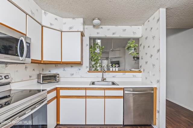 kitchen featuring a toaster, light countertops, appliances with stainless steel finishes, a textured ceiling, and a sink