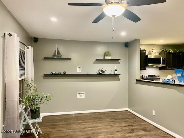 kitchen featuring open shelves, wood finished floors, baseboards, and appliances with stainless steel finishes