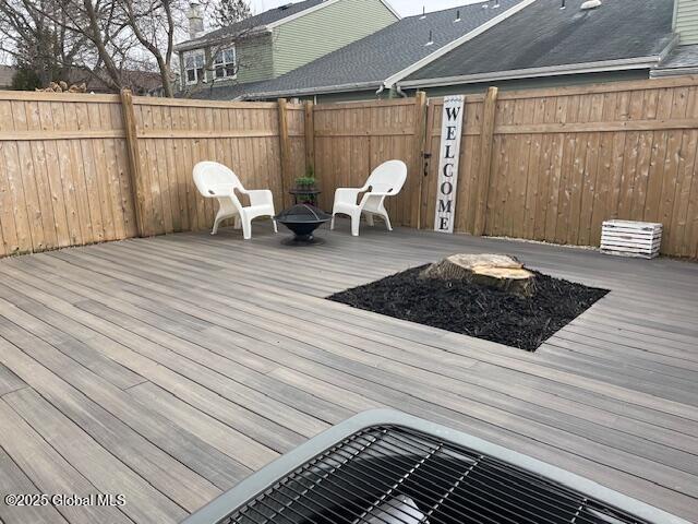 wooden terrace featuring an outdoor fire pit and a fenced backyard