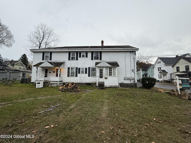 rear view of property featuring entry steps, central air condition unit, and a yard