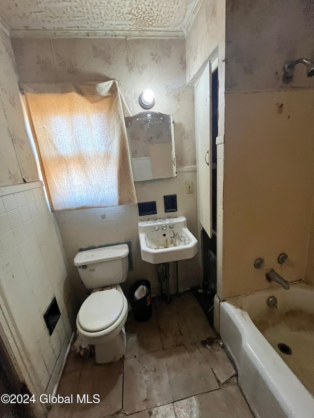 bathroom with wallpapered walls, a sink, and toilet