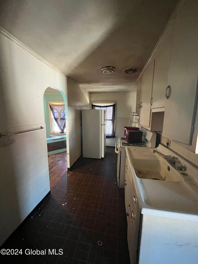 kitchen featuring white cabinetry, light countertops, arched walkways, and white appliances