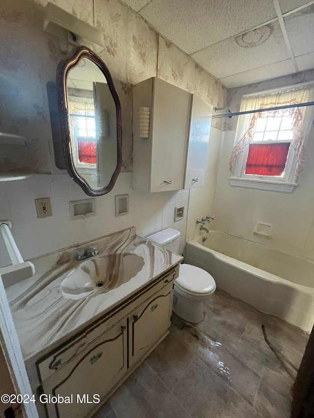 bathroom with bathing tub / shower combination, toilet, a paneled ceiling, and vanity