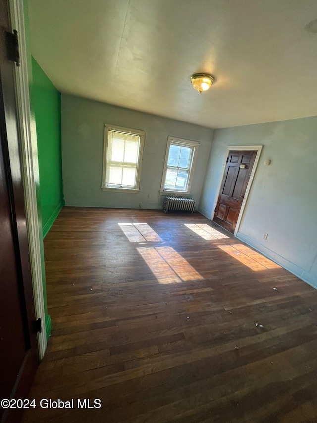 spare room with dark wood-style floors, radiator heating unit, and baseboards