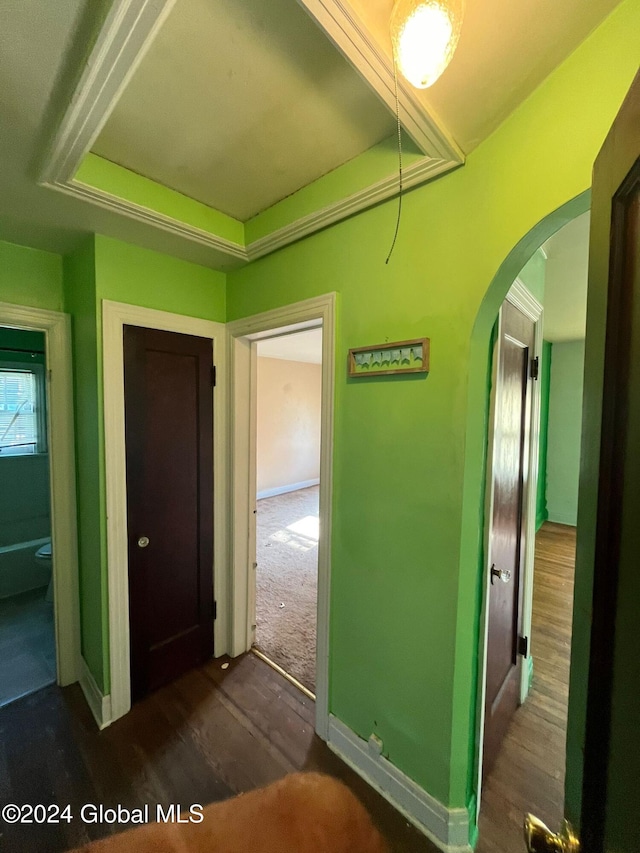 corridor featuring arched walkways, baseboards, and dark wood finished floors