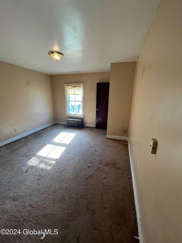 carpeted empty room with baseboards and radiator heating unit