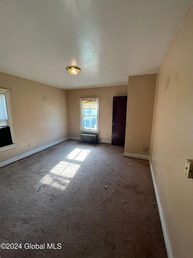 carpeted spare room with radiator and baseboards