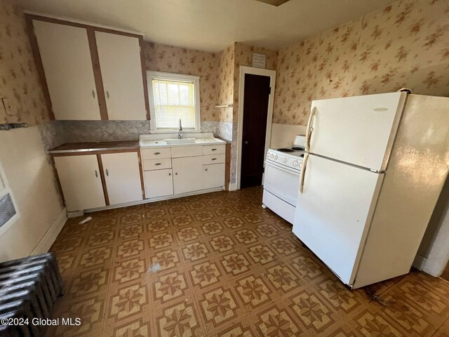 kitchen featuring white cabinetry, white appliances, wallpapered walls, a sink, and light floors