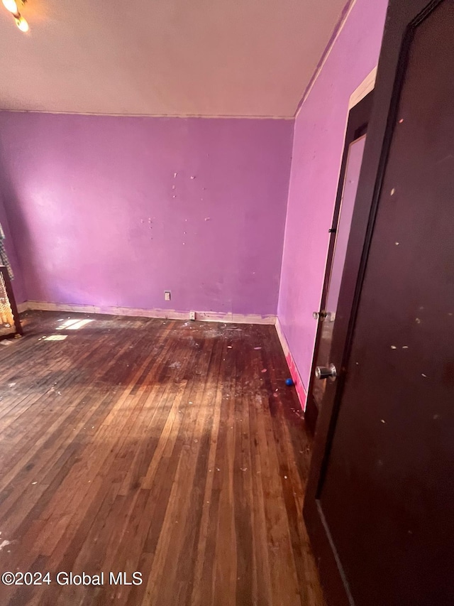unfurnished room with baseboards and wood-type flooring