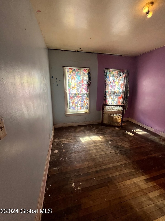 spare room featuring baseboards and hardwood / wood-style flooring