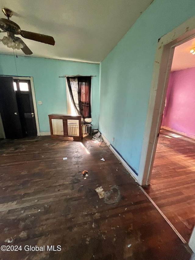 unfurnished living room featuring baseboards, wood finished floors, and ceiling fan