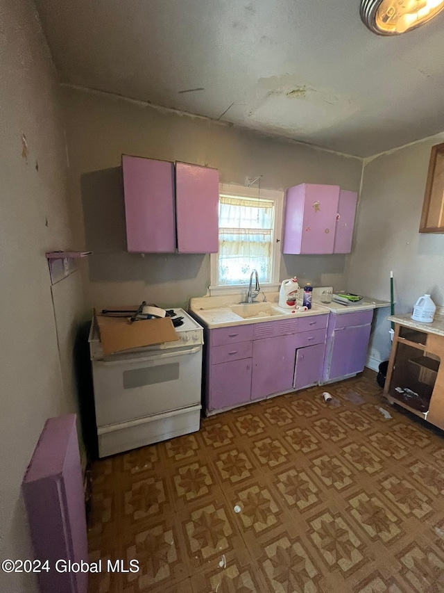 kitchen with light countertops, red cabinetry, a sink, washer / clothes dryer, and white electric range