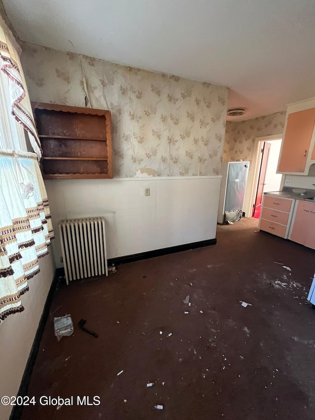 unfurnished room with radiator heating unit and wallpapered walls