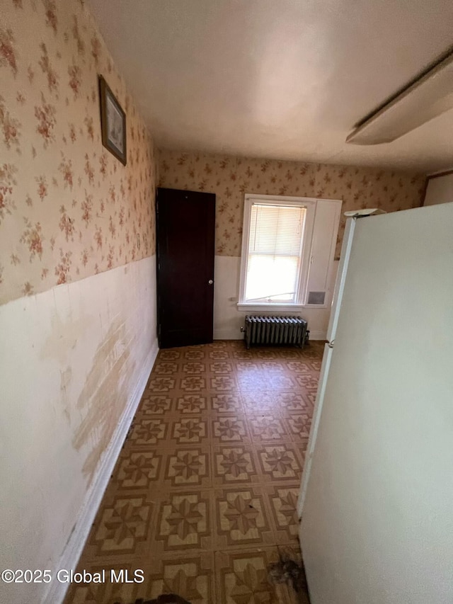 hallway featuring radiator heating unit, wallpapered walls, a wainscoted wall, and tile patterned floors